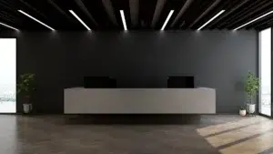 Modern office reception illuminated by Mount Lighting’s M-Line Low Glare Linear Lighting, featuring a sleek marble desk, dark feature wall, and soft natural daylight for balanced ambience.